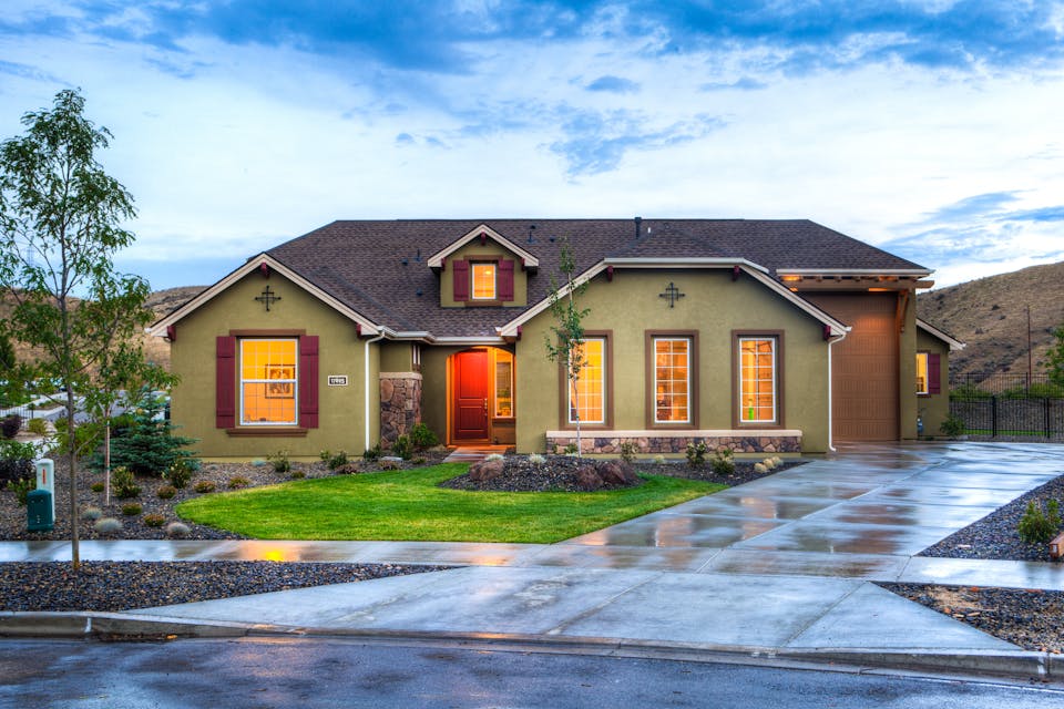 Well-kept suburban home front with driveway, lawn, and garage door at dusk